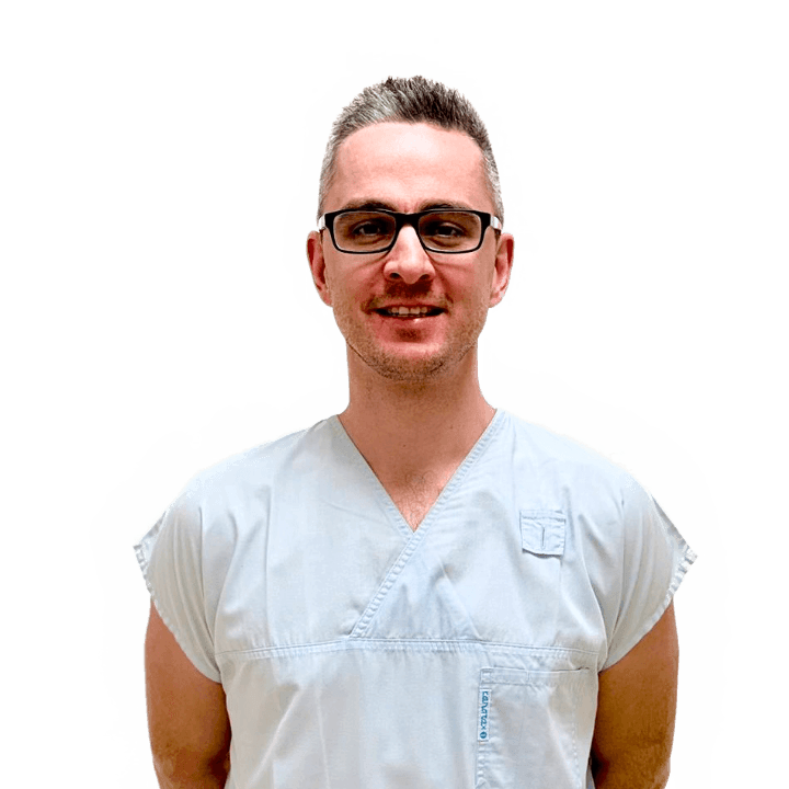 Portrét usmívajícího se muže v brýlích a světle šedém lékařském oděvu na bílém pozadí.